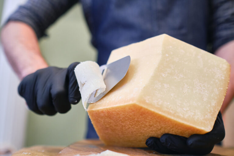 Young worker slicing cheese in shop.selective focus