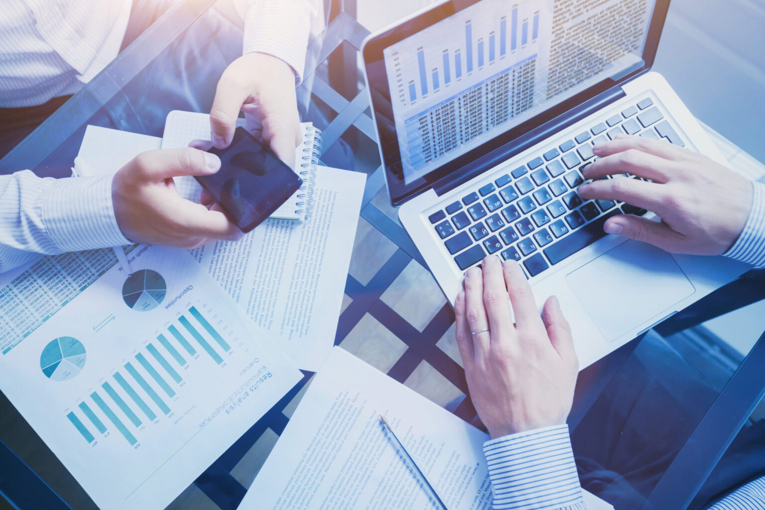 Person with a laptop sitting at the table, some charts and papers around