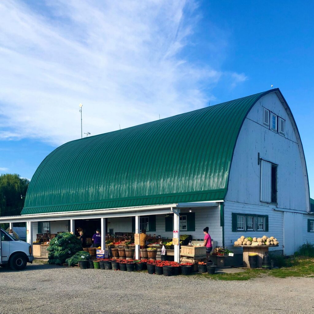 Farm market outside a barn with fresh produce for sale, supporting small farms and local sourcing